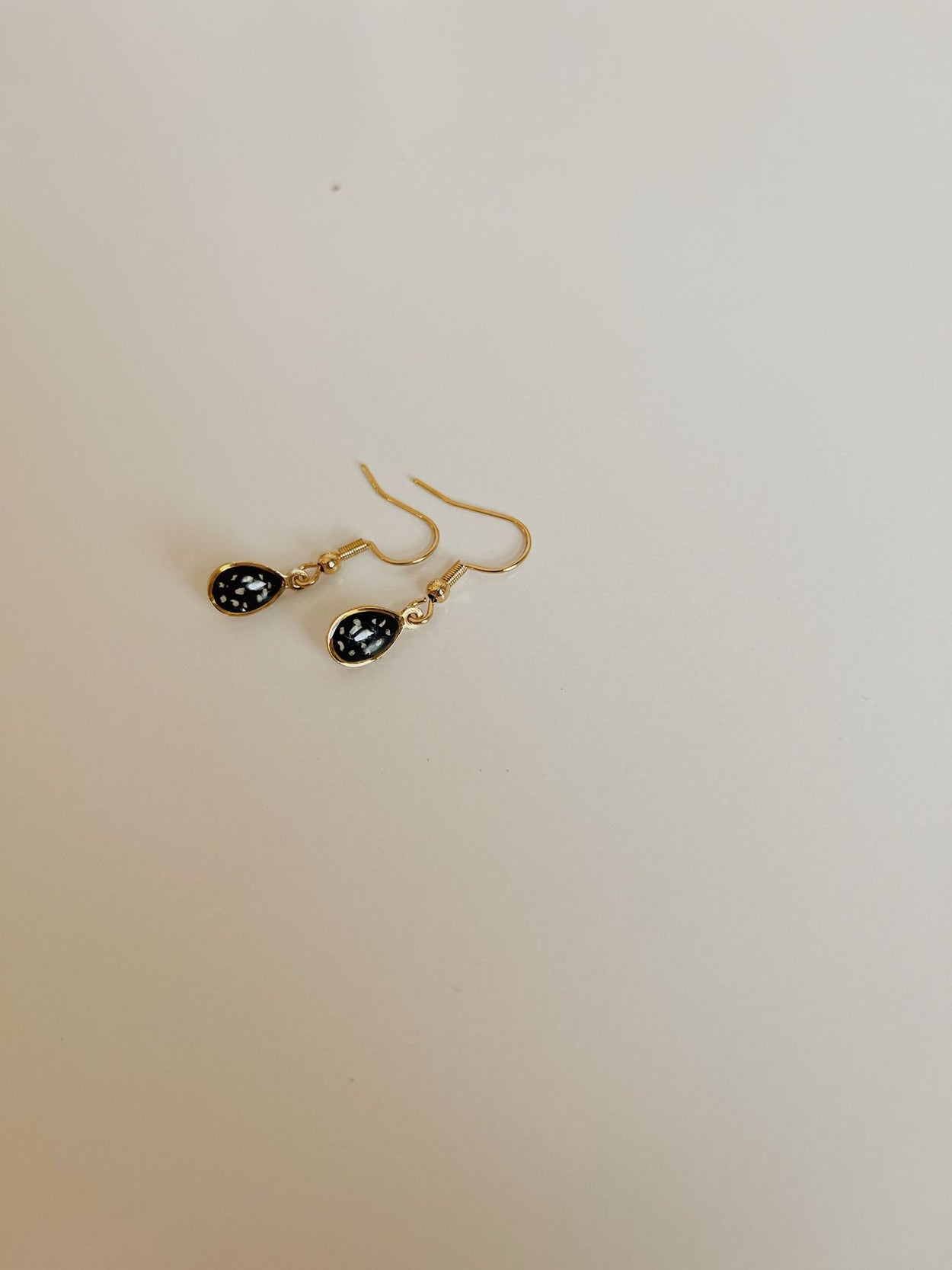 Gold earrings with black stones on a beige background