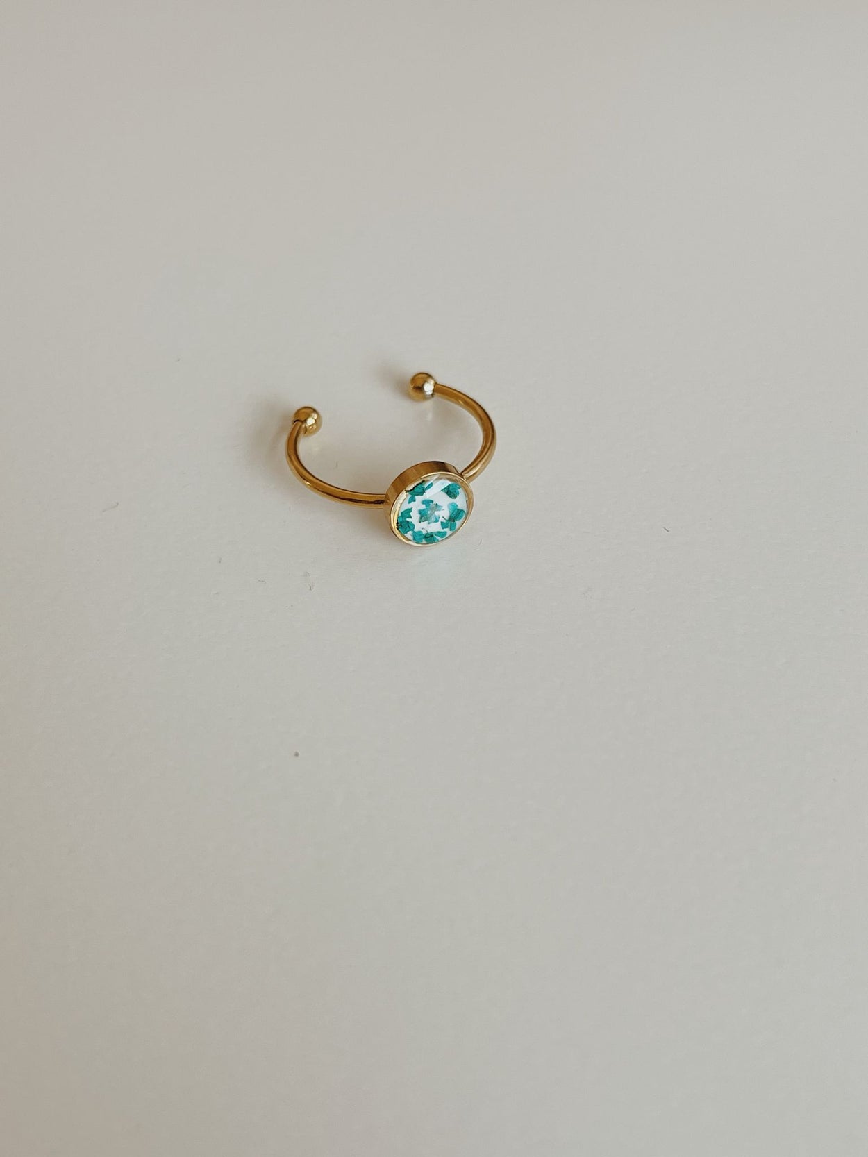 Gold ring with a blue gemstone on a light gray background