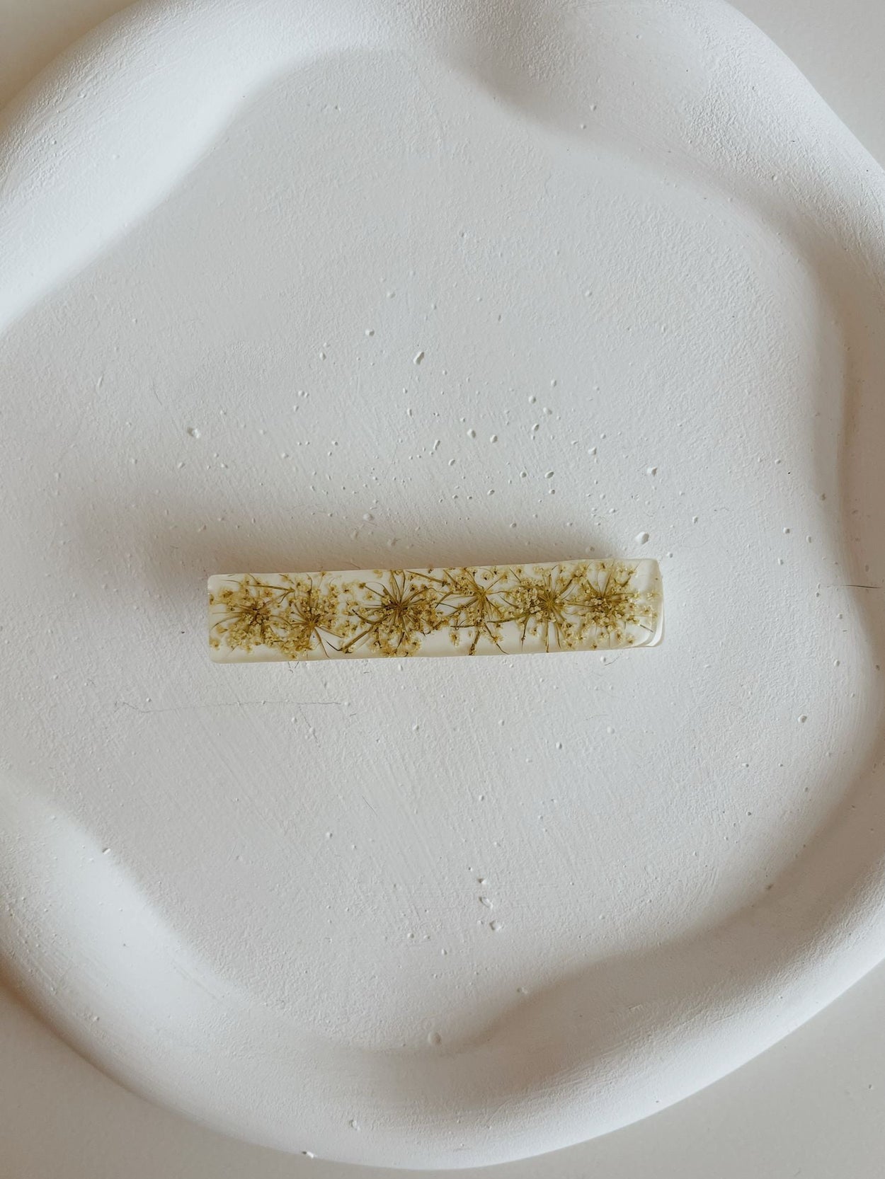 Small rectangular hair clip with floral patterns on a white plate