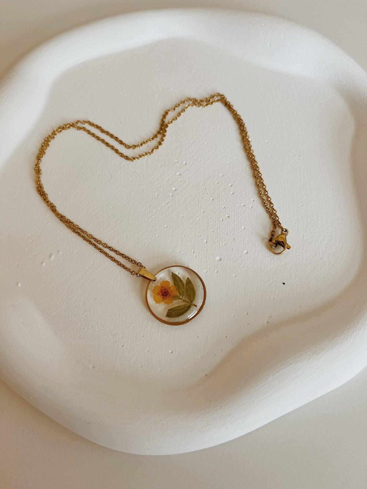 Necklace with a floral pendant on a white plate