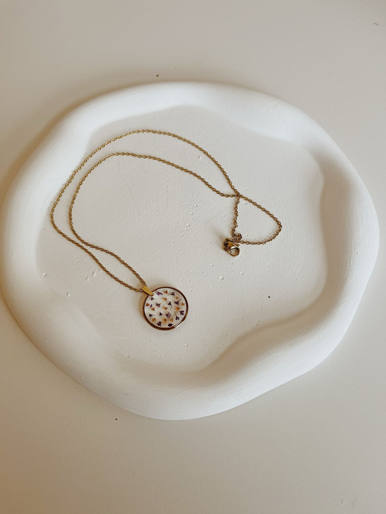 Necklace with a round pendant on a white dish
