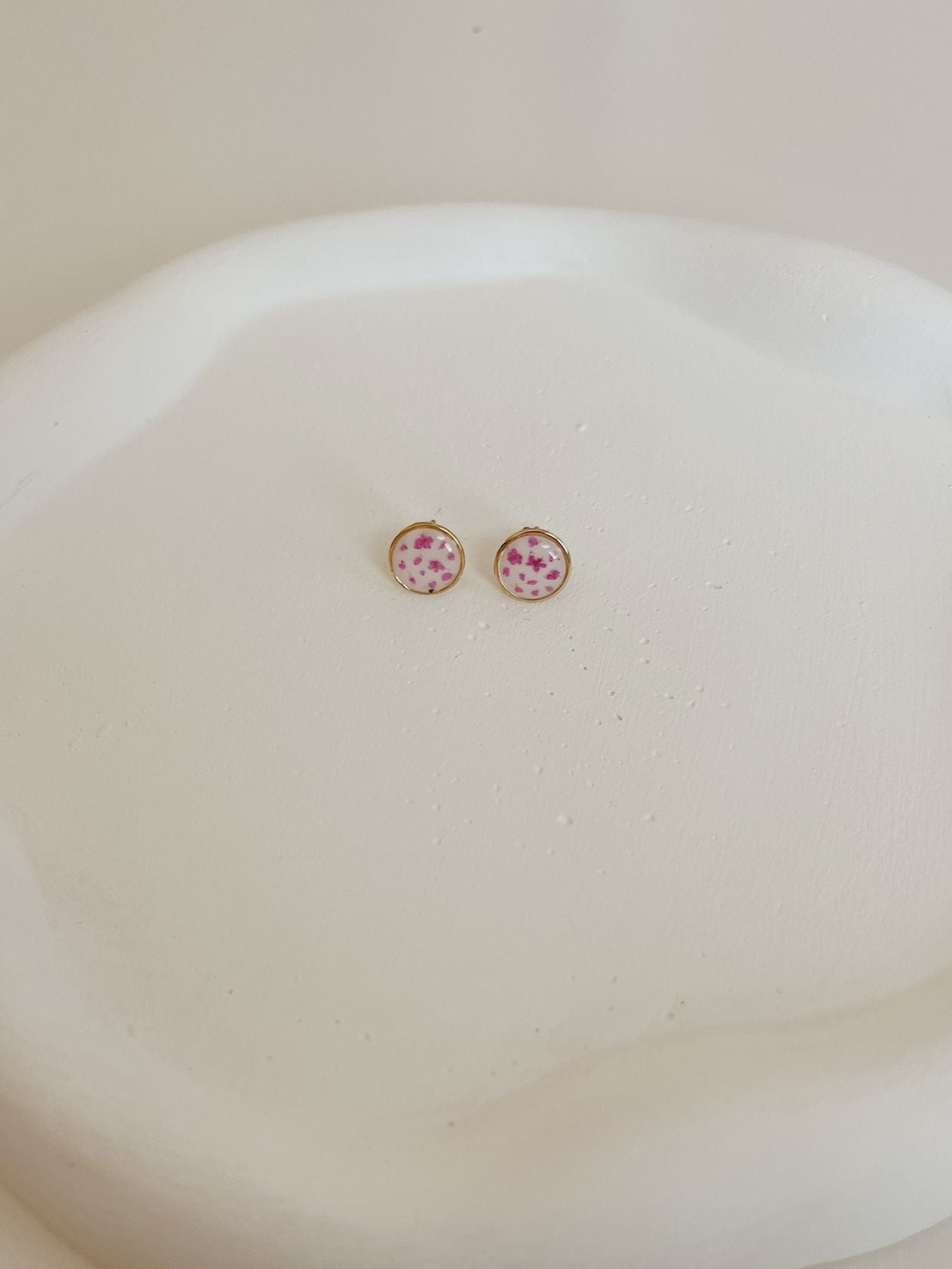 Pair of earrings with pink stones on a white dish