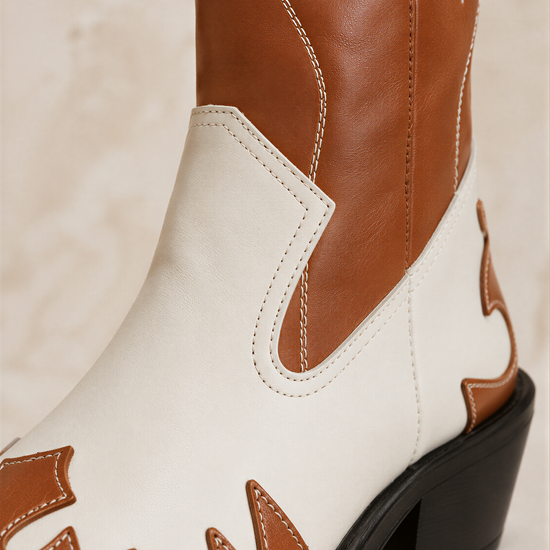 A close-up view of a brown and white cowboy boot, showcasing its distinctive stitching and design.