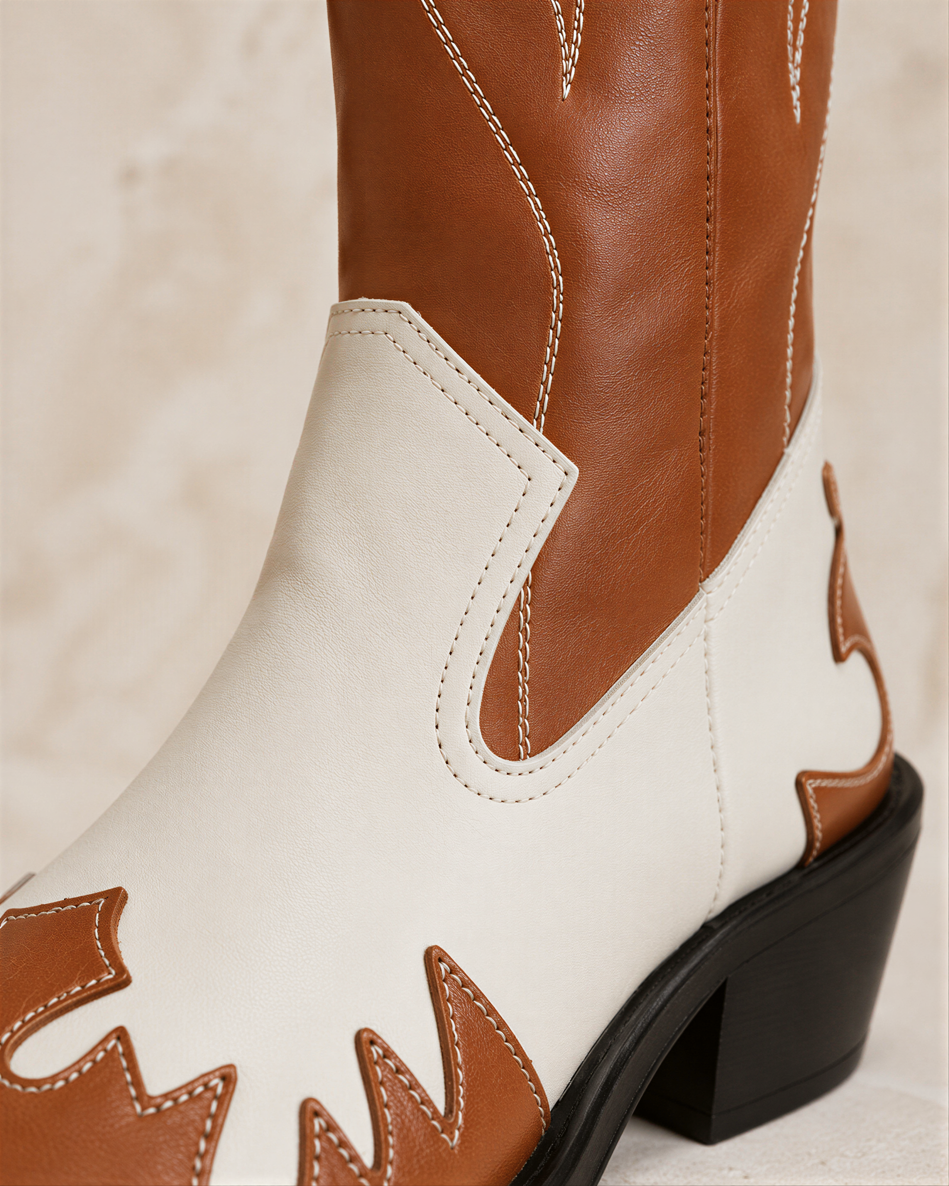 A close-up view of a brown and white cowboy boot, showcasing its distinctive stitching and design.