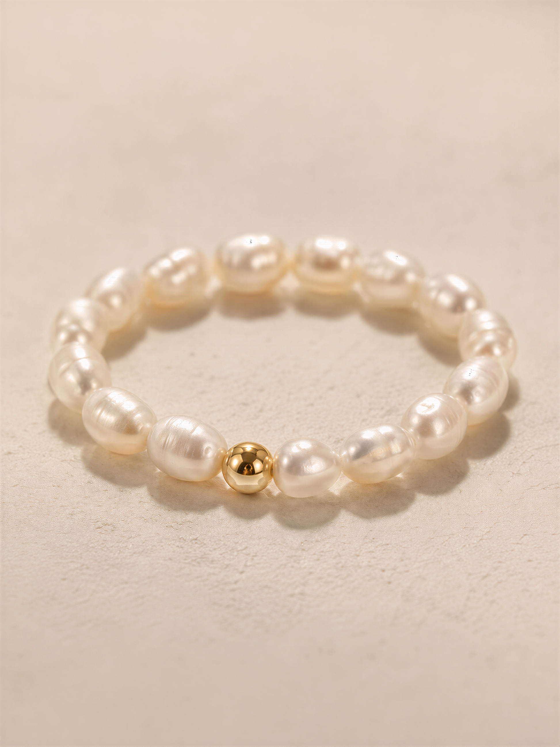A bracelet made of white pearls and a single gold-colored pearl.