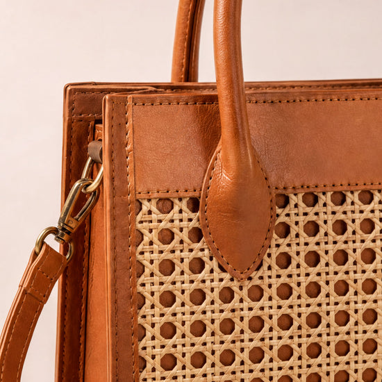 A brown leather handbag with a woven pattern on the front.