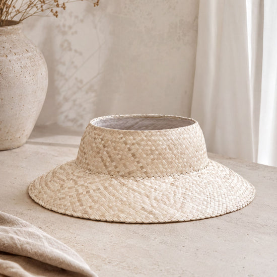 a straw hat with a woven pattern, placed on a light-colored surface.
