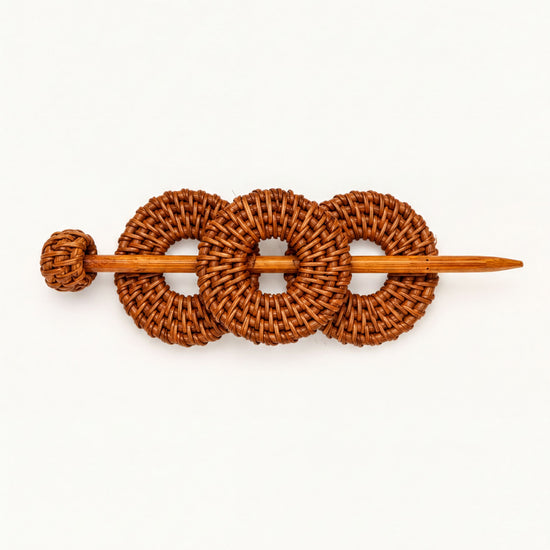 A wooden hair accessory with three woven circles, resembling a hair clip or bobby pin.