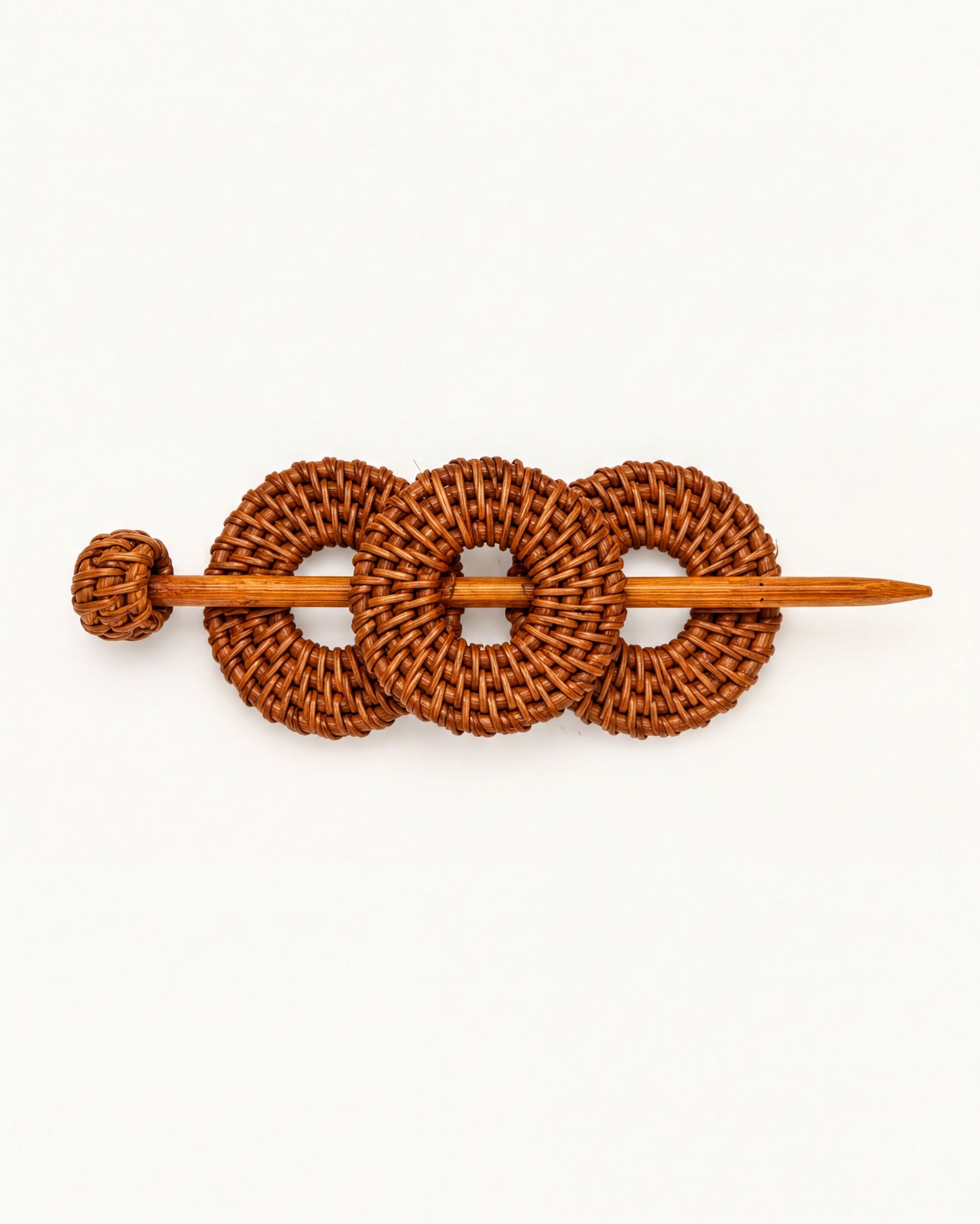 A wooden hair accessory with three woven circles, resembling a hair clip or bobby pin.