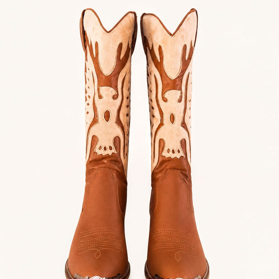 A pair of brown cowboy boots with decorative designs on the sides.