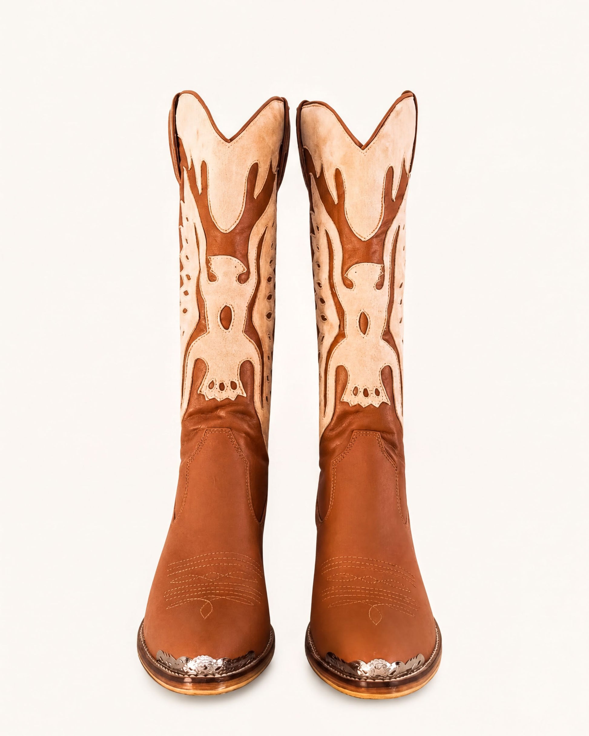 A pair of brown cowboy boots with decorative designs on the sides.