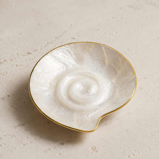 A white seashell with a gold rim is shown in the center of the image.