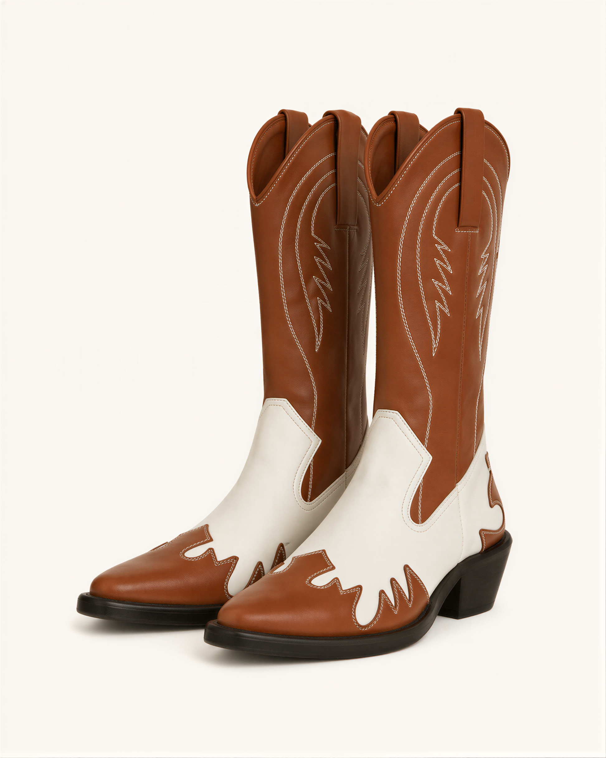 A pair of brown and white cowboy boots against a white background.
