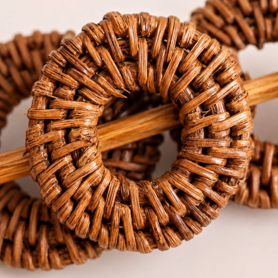 a close-up view of a woven object, possibly a piece of furniture or a decorative item, with a wooden stick or pole extending from it.