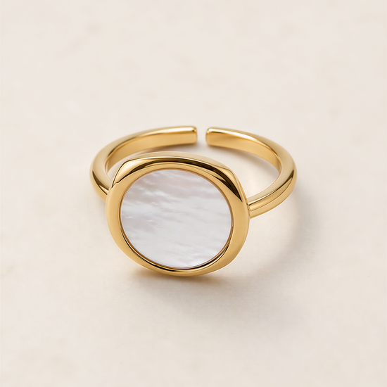 A gold ring with a white oval-shaped stone in the center.