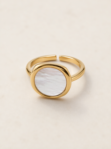 A gold ring with a white oval-shaped stone in the center.
