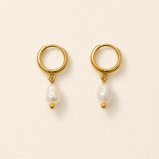A pair of gold earrings with a pearl hanging from each earring.
