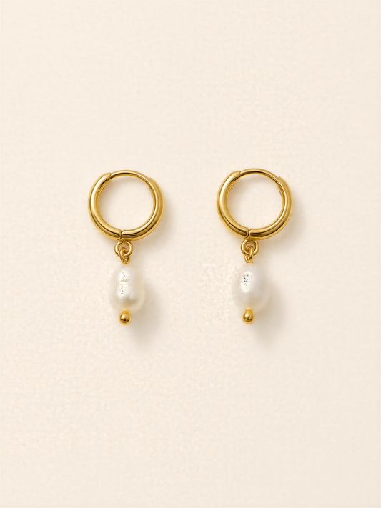 A pair of gold earrings with a pearl hanging from each earring.