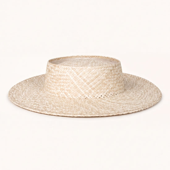 A straw hat with a wide brim and a round crown, sitting on a plain white background.