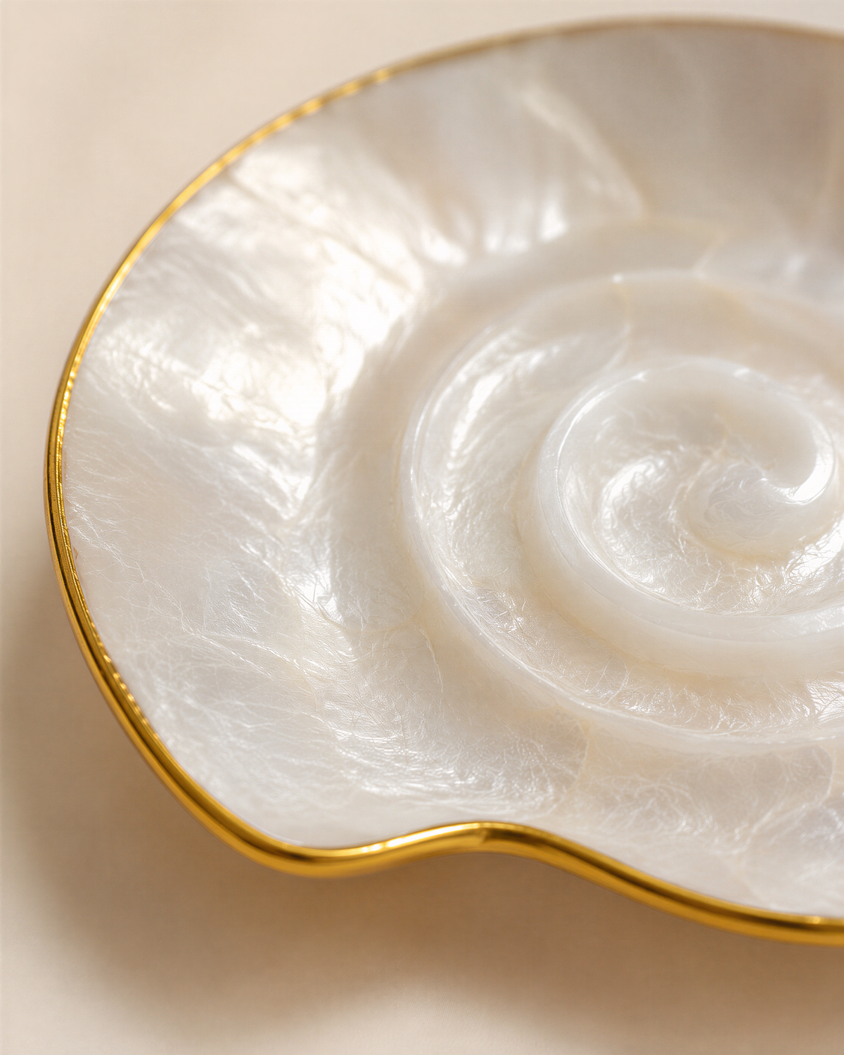 A close-up image of a white, spiral-shaped object with a gold rim, resting on a light-colored surface.