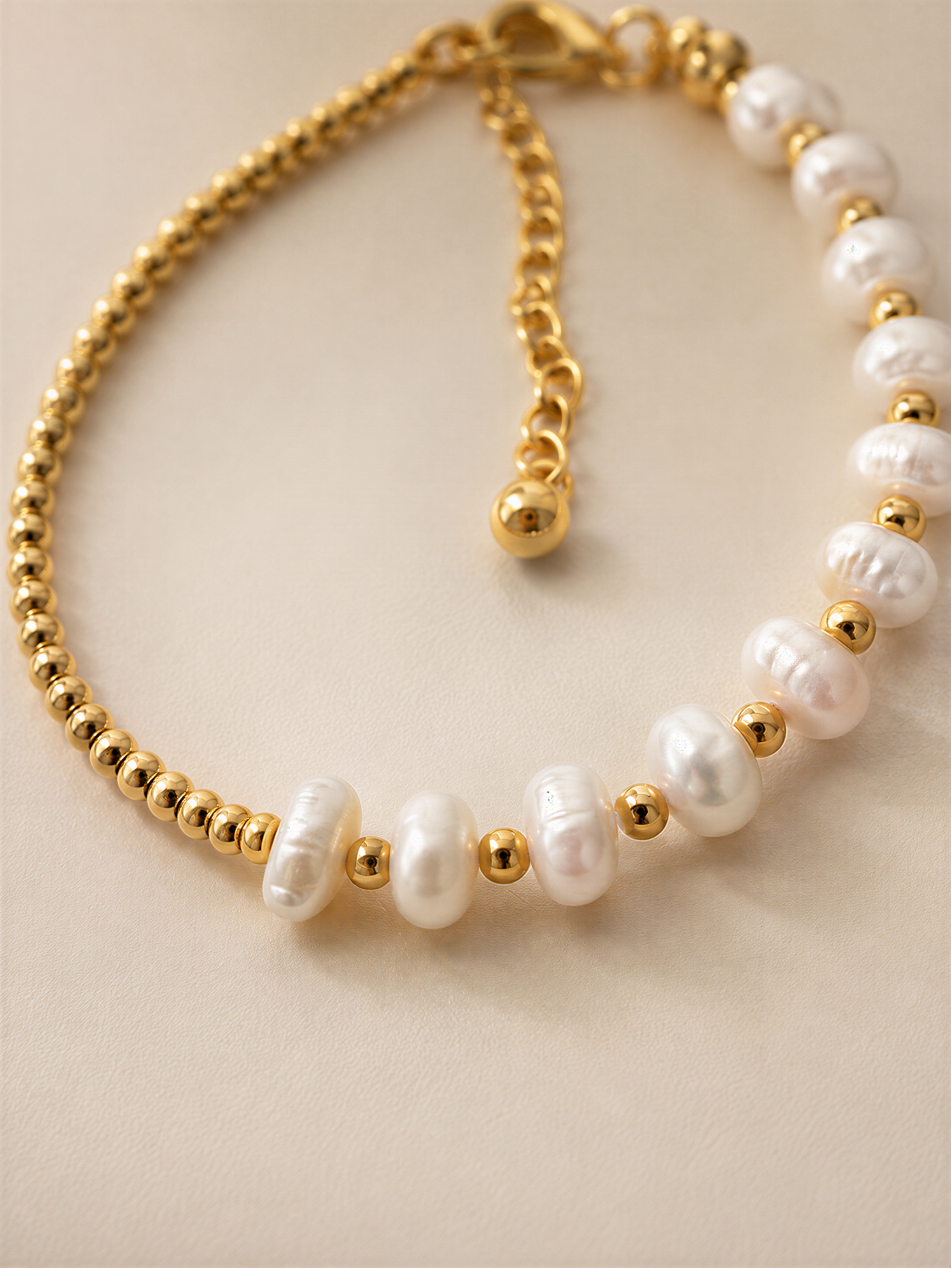 A gold-colored necklace with white pearls and gold beads.