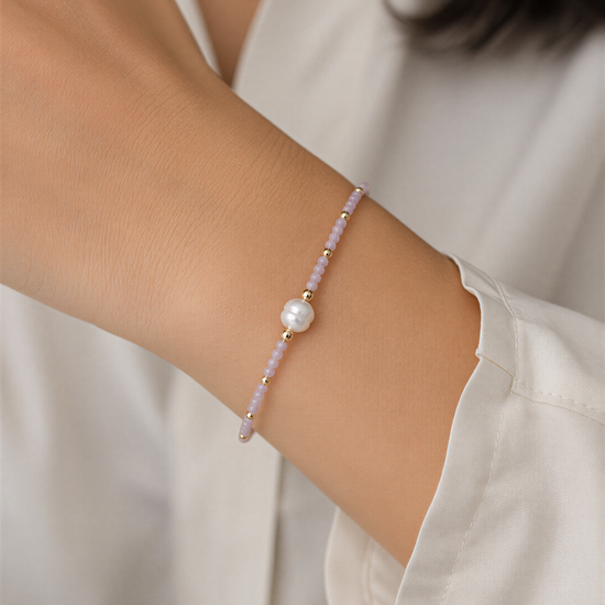 A person wearing a white shirt and bracelet on their wrist.