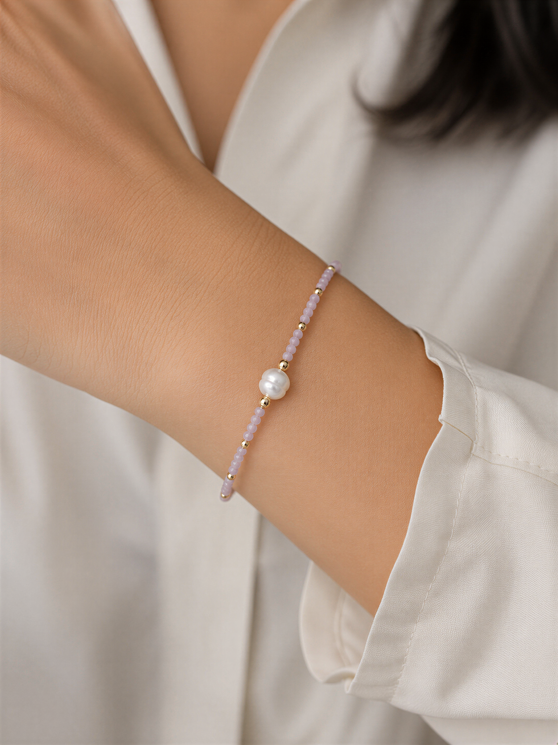 A person wearing a white shirt and bracelet on their wrist.