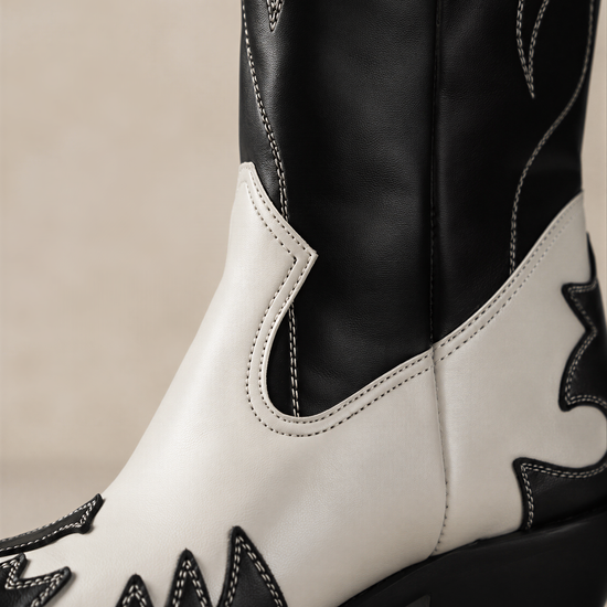 A close-up of a black and white cowboy boot, focusing on the side profile and the stitching.