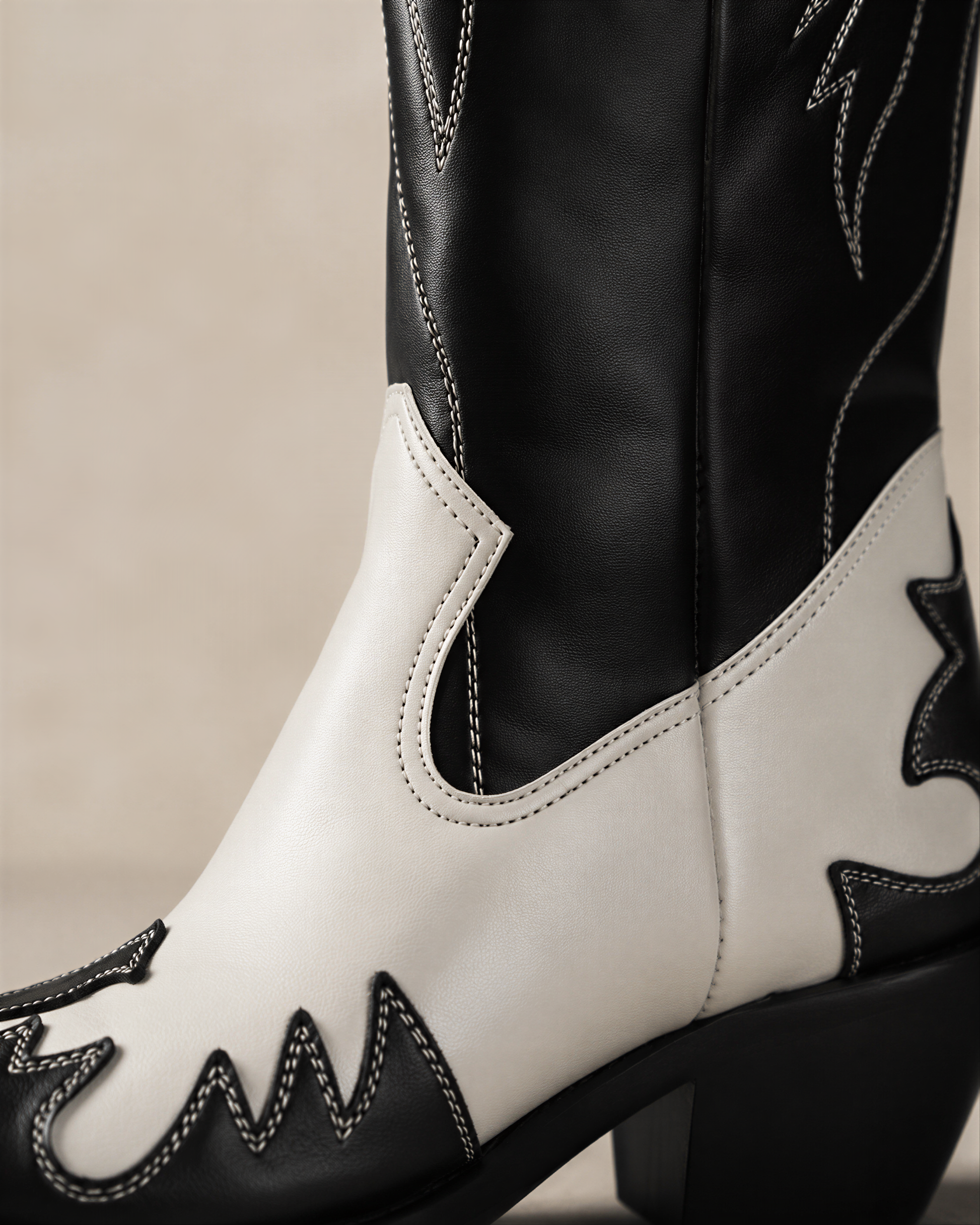 A close-up of a black and white cowboy boot, focusing on the side profile and the stitching.