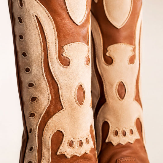 A close-up view of a pair of brown leather cowboy boots with intricate designs and patterns.