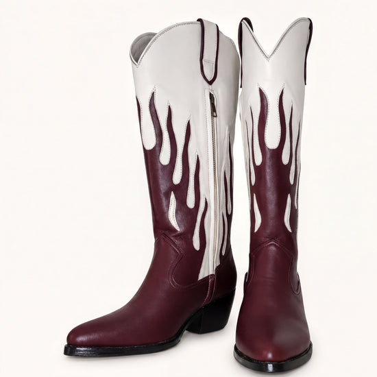 A pair of burgundy cowboy boots with white flames on the sides, standing upright against a white background.