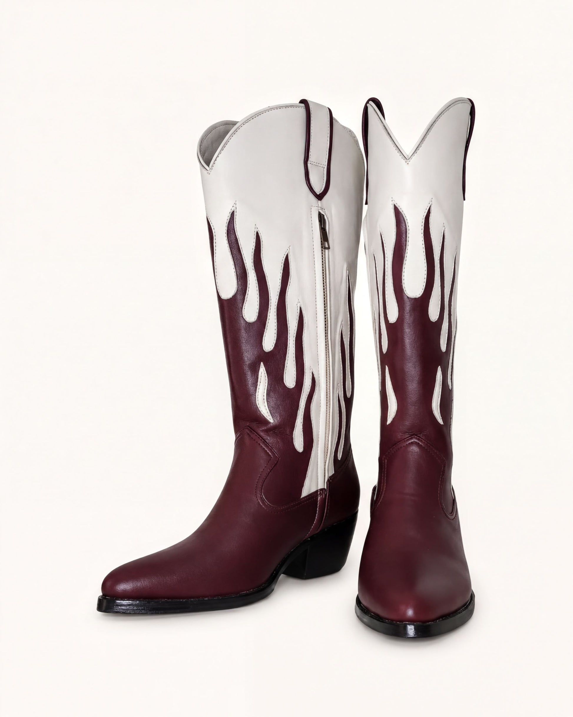 A pair of burgundy cowboy boots with white flames on the sides, standing upright against a white background.