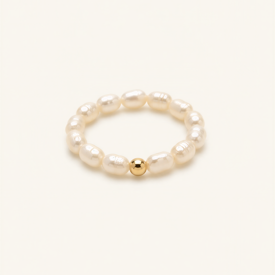 A bracelet made of white pearls and a single gold bead.