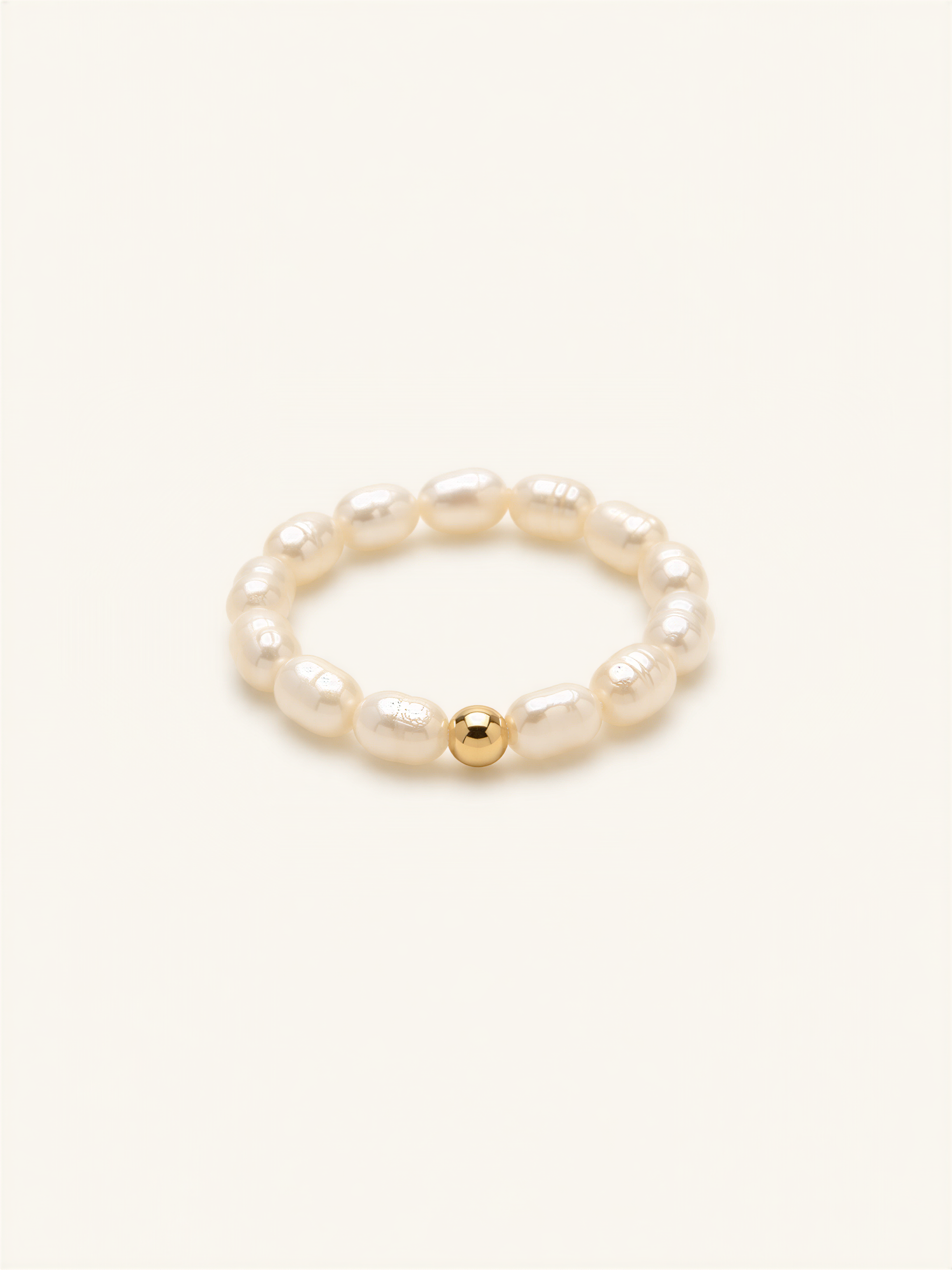 A bracelet made of white pearls and a single gold bead.