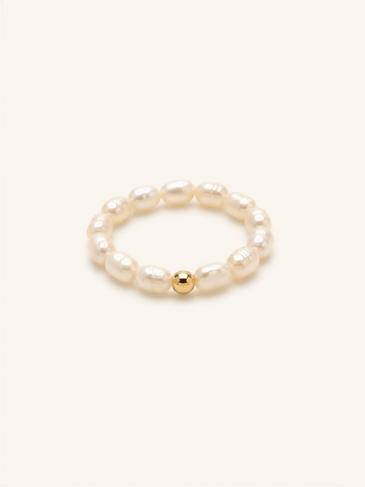 A bracelet made of white pearls and a single gold bead.