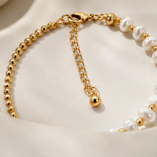 A close-up view of a gold necklace with white pearls and a clasp.