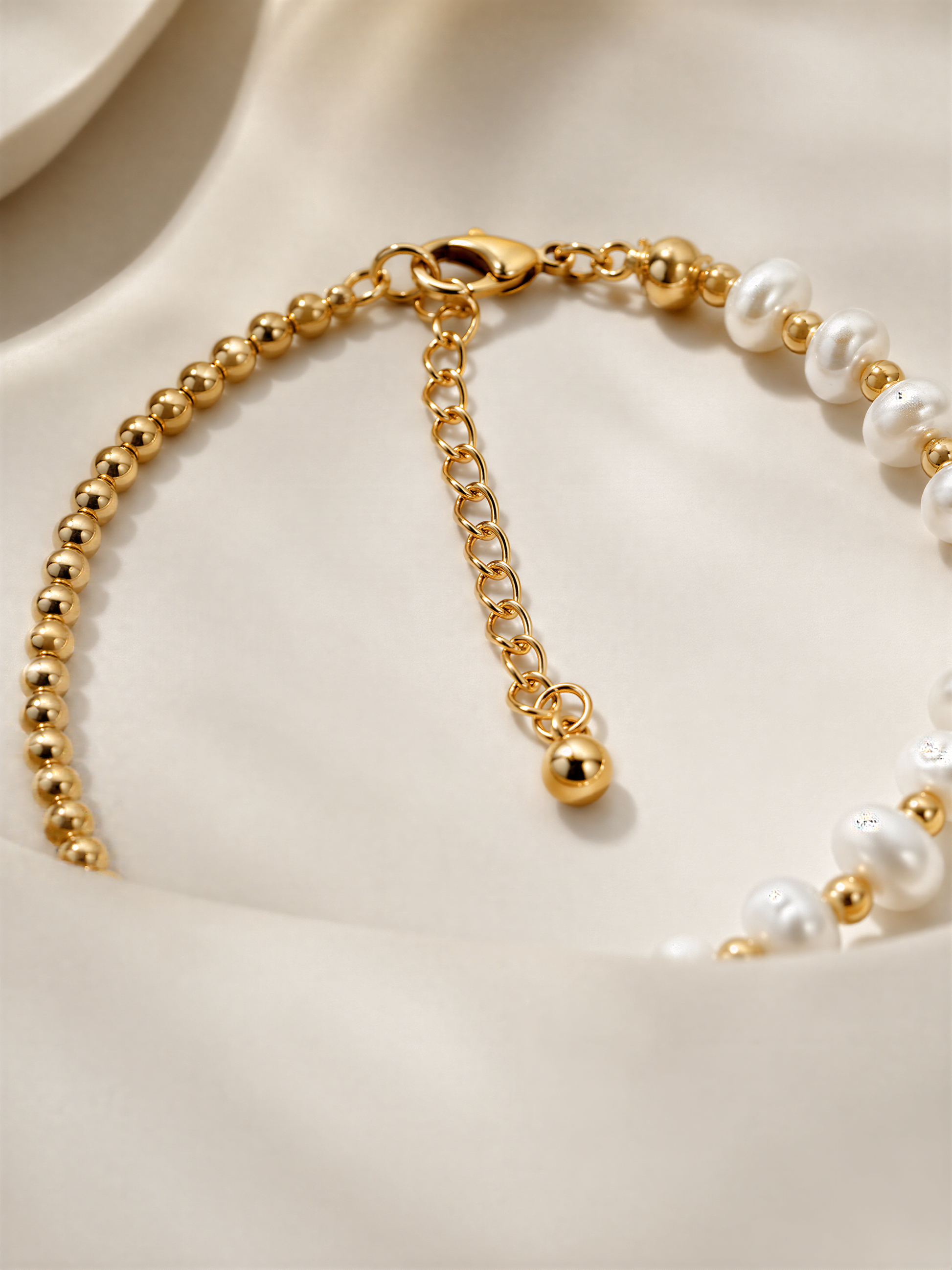 A close-up view of a gold necklace with white pearls and a clasp.