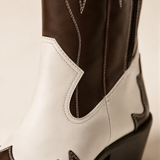A close-up view of a brown and white cowboy boot, showcasing the stitching and design details.