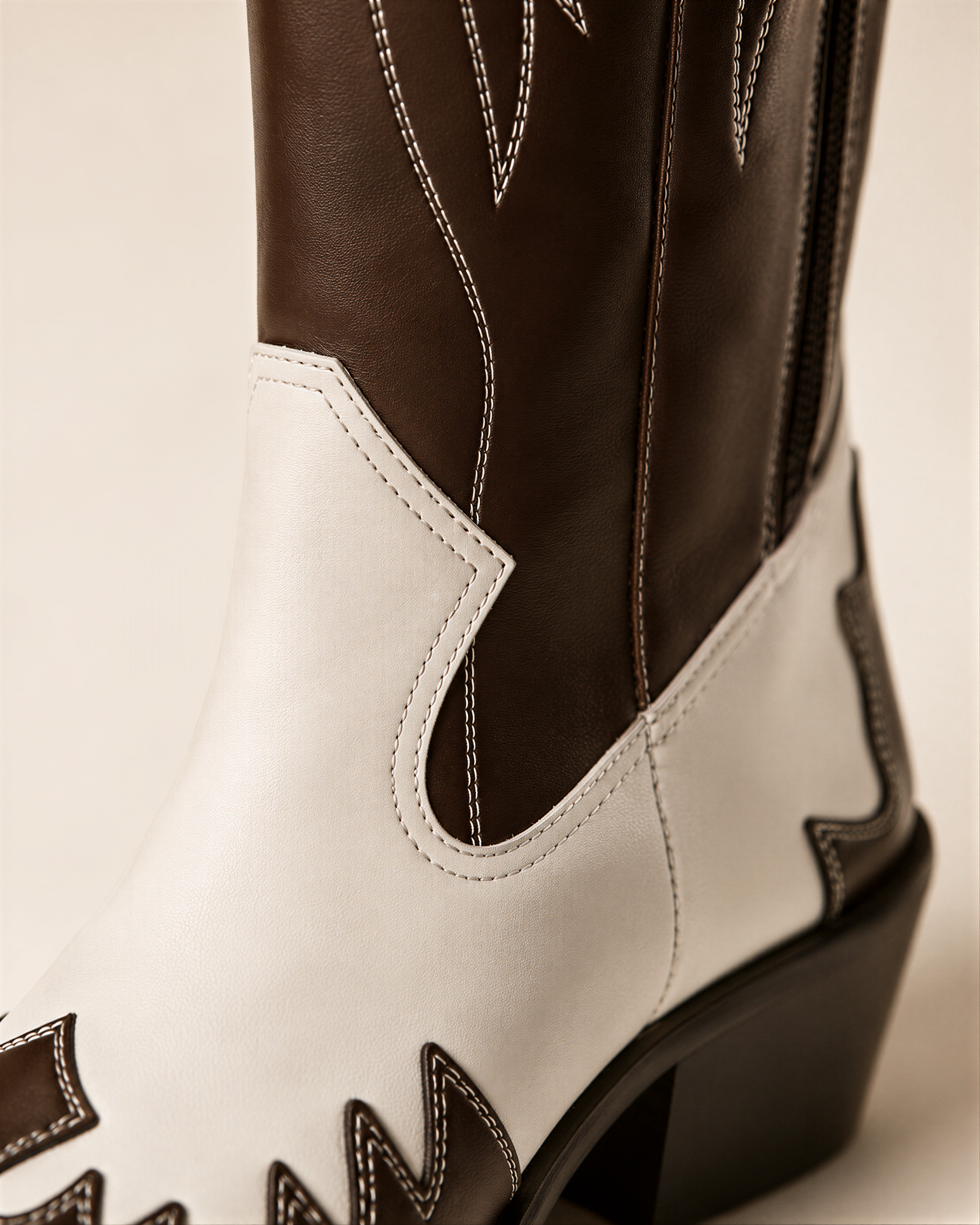 A close-up view of a brown and white cowboy boot, showcasing the stitching and design details.