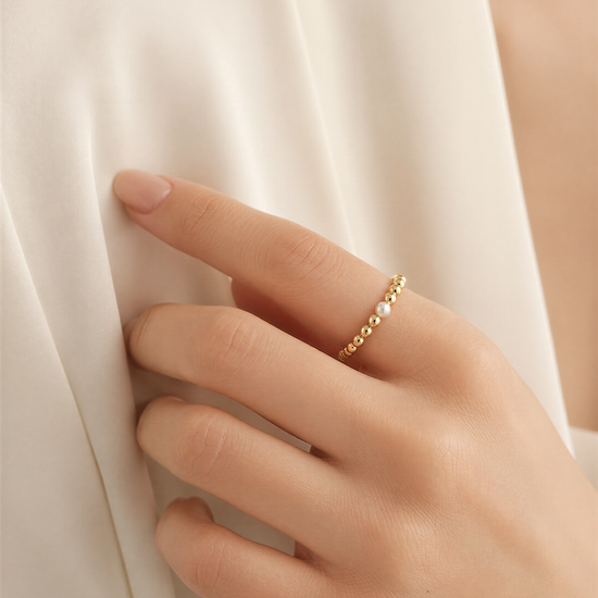 A close-up of a hand wearing a gold ring with small stones on the fingers.