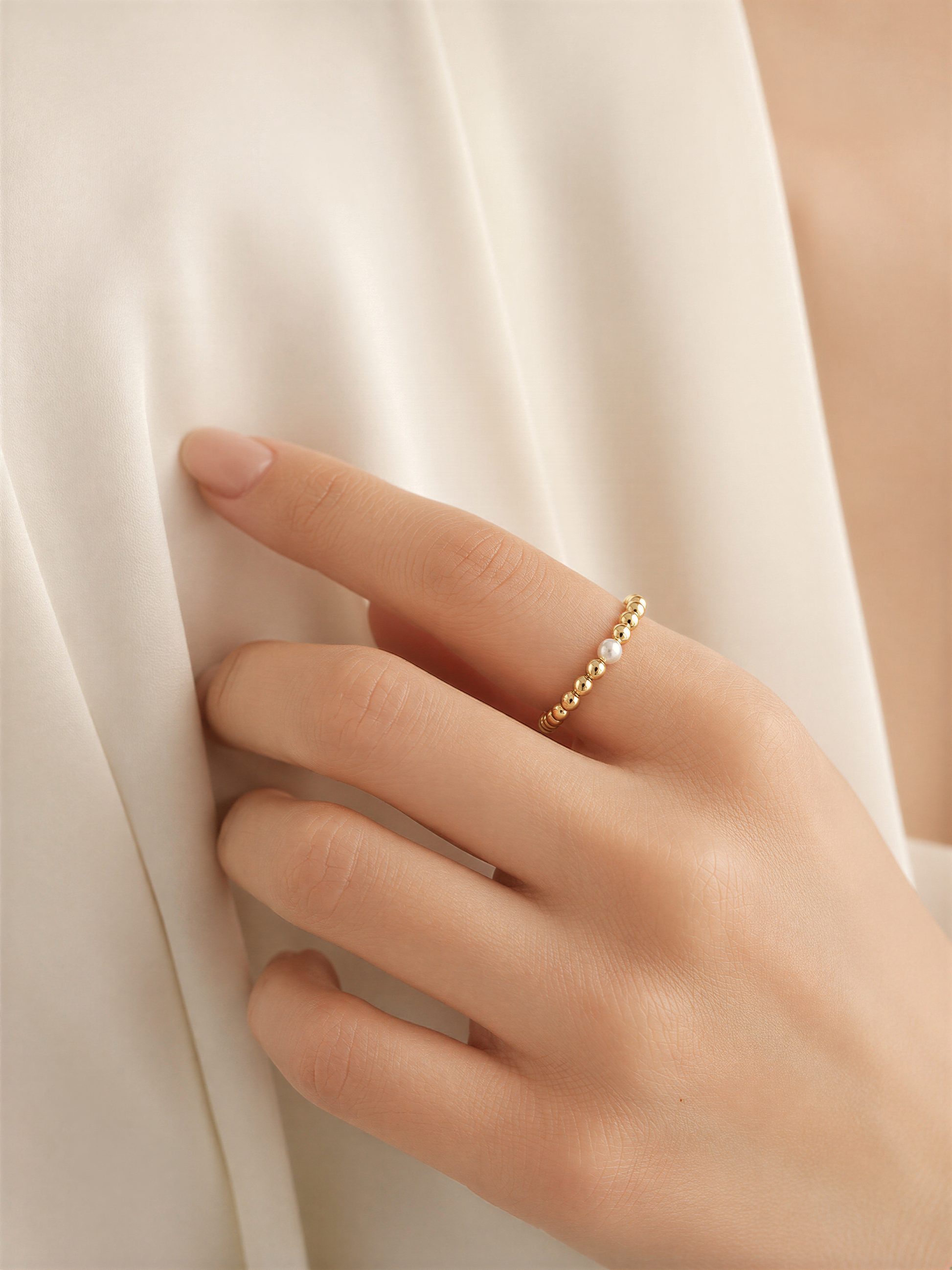 A close-up of a hand wearing a gold ring with small stones on the fingers.
