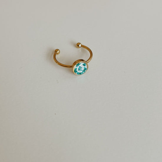 Gold ring with a blue gemstone on a light gray background