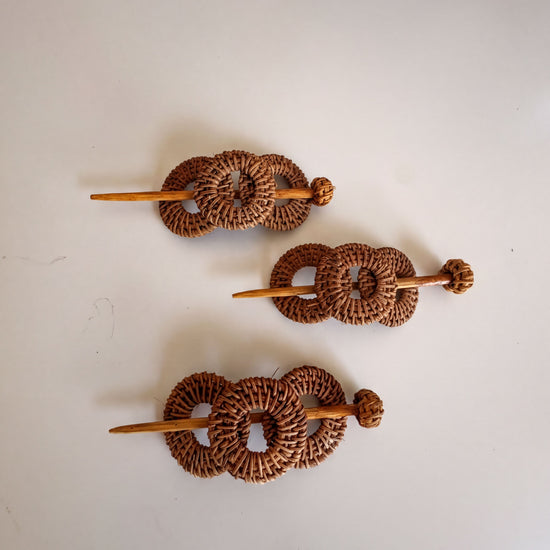 Three woven hair clips made of brown wicker material, each with a wooden stick.