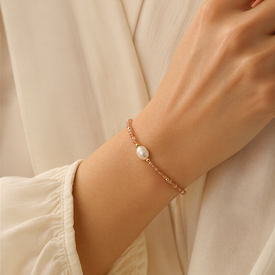 A close-up of a person's wrist wearing a bracelet with a pearl bead.