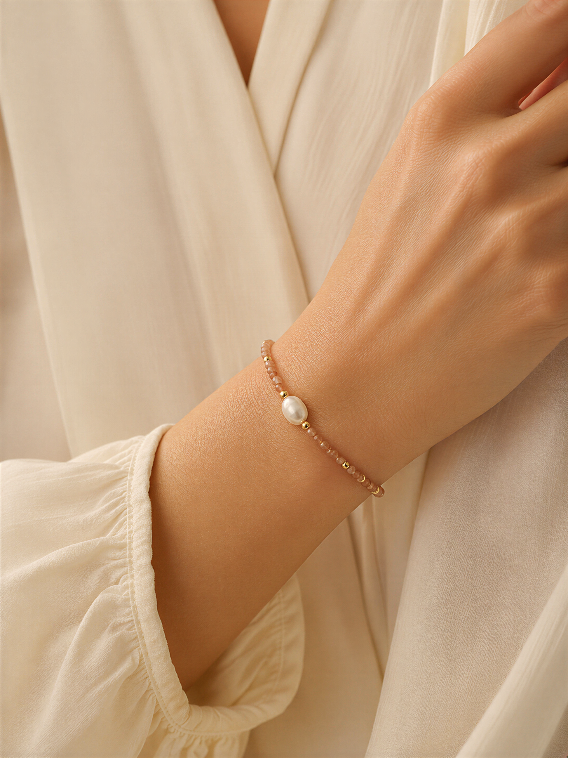 A close-up of a person's wrist wearing a bracelet with a pearl bead.