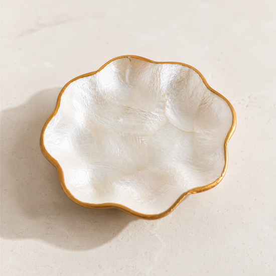 A white ceramic bowl with a gold rim is placed on a light-colored surface.