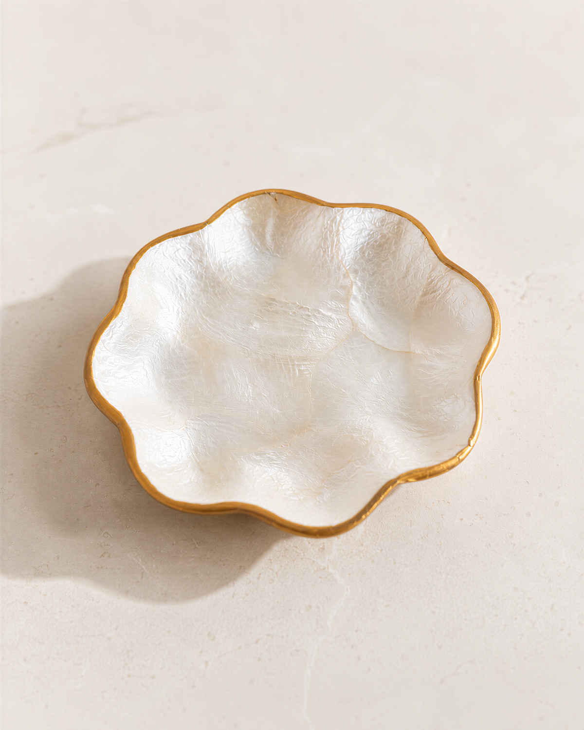 A white ceramic bowl with a gold rim is placed on a light-colored surface.