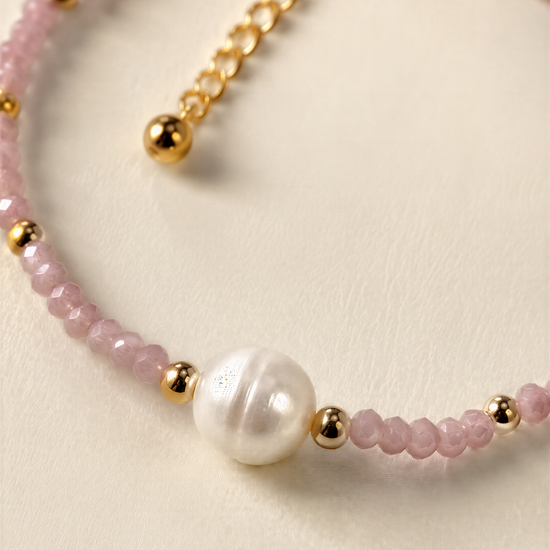 A delicate necklace with a combination of pink and white beads, accented by a large white pearl at the center.