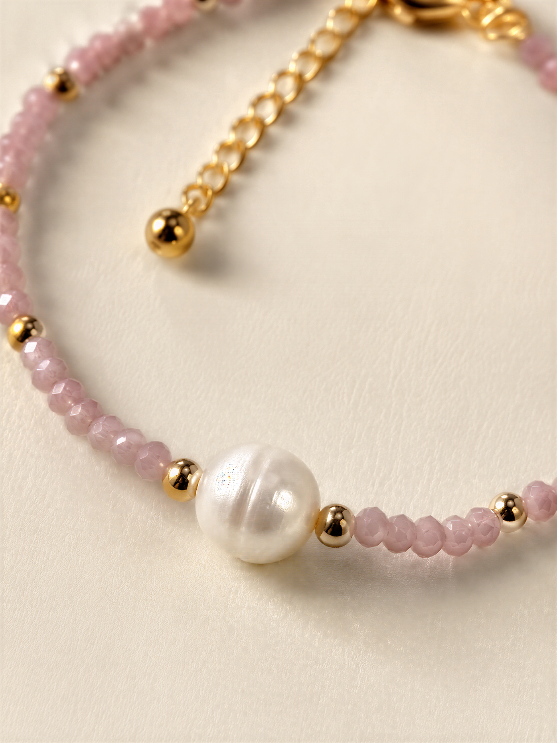A delicate necklace with a combination of pink and white beads, accented by a large white pearl at the center.