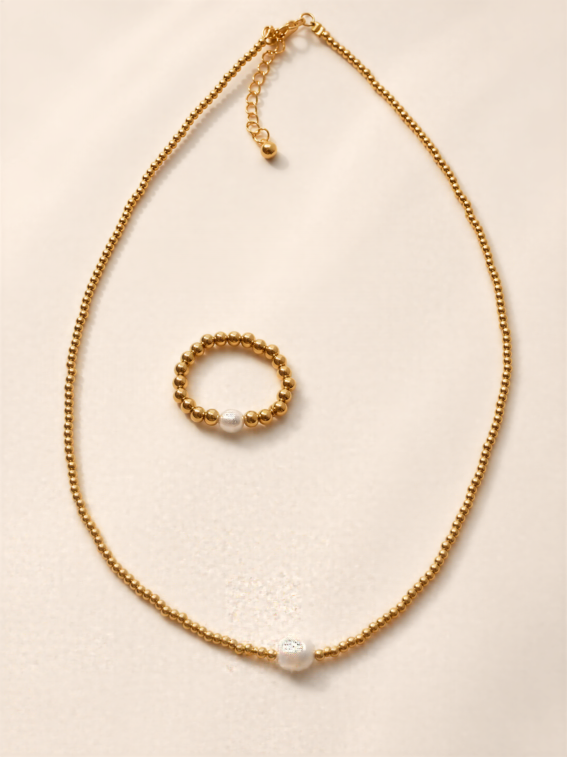 a gold necklace with a pearl pendant and a small gold bead bracelet.